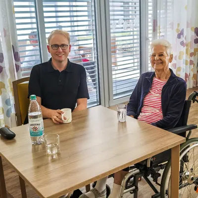 Man sieht Stephan Klotz mit seiner Großtante Greta im Pflegeheim Haus Taubergießen in Kappel-Grafenhausen am Kaffeetisch sitzen.