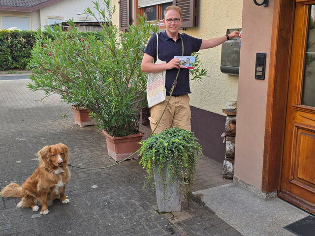 Man sieht Stephan Klotz mit seinem Hund Yoshi beim Verteilen der Flyer