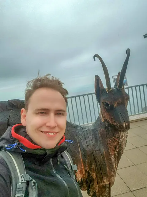 Stephan Klotz steht neben einer Gams aus Holz auf dem Großglockner.