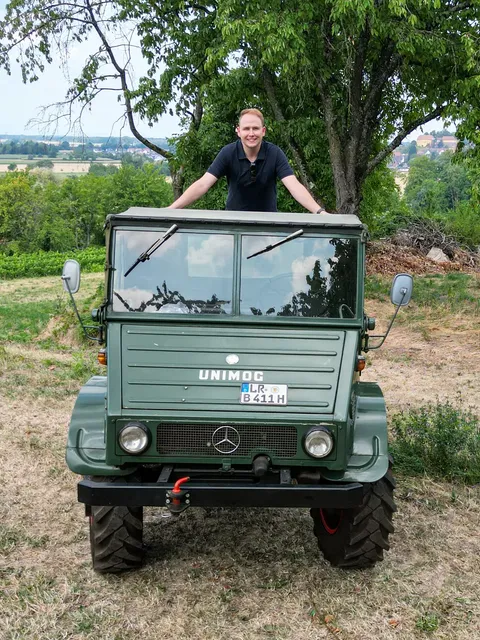 Stephan Klotz steht auf seinem Unimog auf der grüne Streuobstwiese