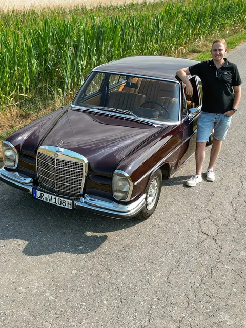 Stephan Klotz steht auf der Straße neben seinem Mercedes-Benz W108.