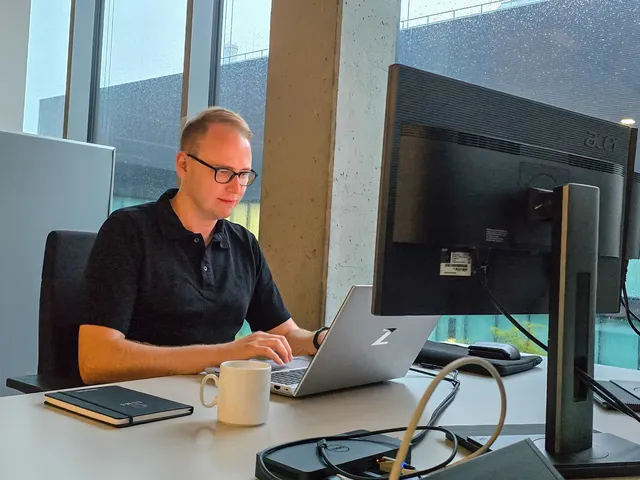 Stephan Klotz sitzt an seinem Arbeitsplatz bei der Mercedes-Benz AG in Sindelfingen und arbeitet an seinem Laptop.